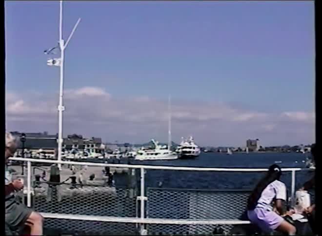 Vintage home video captures a family's boat tour through a bustling city harbor on a sunny day