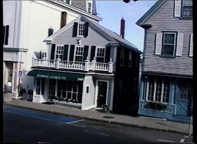 Archival footage from the 1990s slowly pans across a quiet, picturesque street in a historic American town