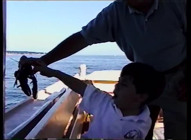 Vintage footage captures a touching moment as a young boy waves goodbye to a lobster being released back into the ocean from a boat