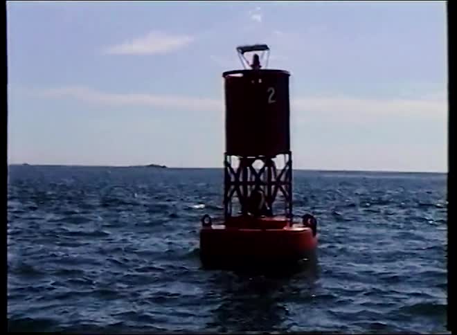 Vintage footage shows a red channel marker buoy bobbing up and down in the open ocean