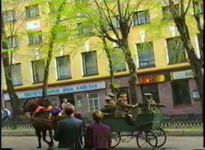 Vintage VHS footage shows a historical reenactment parade with soldiers on a horse-drawn Tachanka machine gun cart in a Russian city