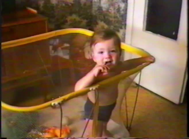 Authentic VHS footage of a cheerful baby boy standing in his playpen and looking at the camera