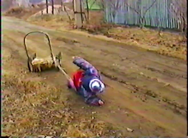 A funny vintage clip shows a small child falling in the mud while playing with a sled, then getting back up to continue playing