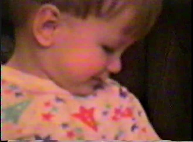 An adorable toddler with a bright smile looks at the camera from his wooden indoor swing