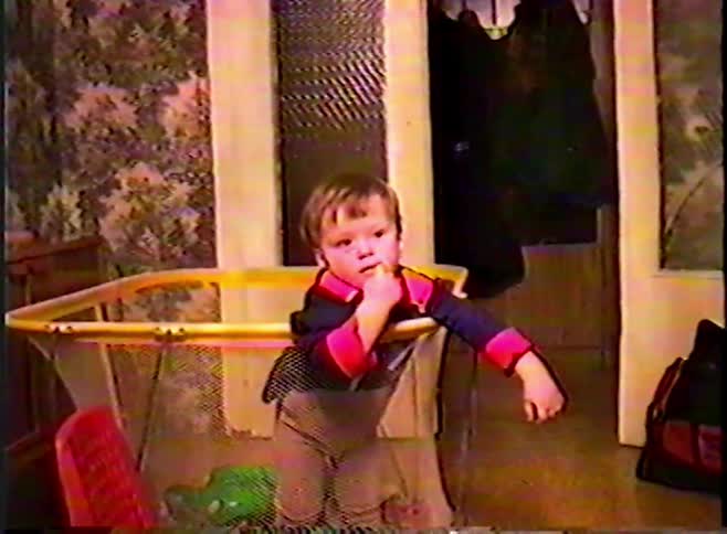 Vintage VHS footage shows a cute toddler standing up inside a playpen at home