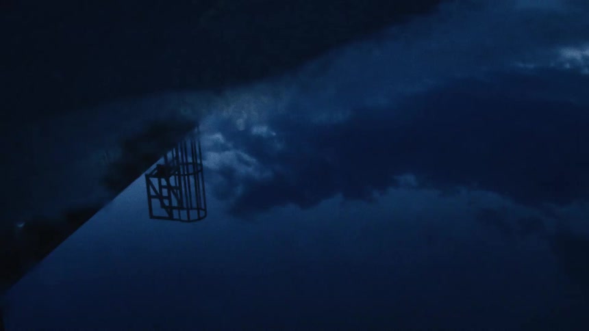 A silhouetted basketball hoop is illuminated by flashes of lightning against a dark and stormy night sky