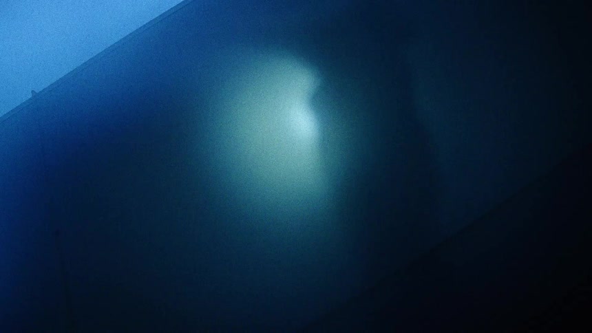 The mysterious shadow of a person moves and dances behind a dark blue translucent surface
