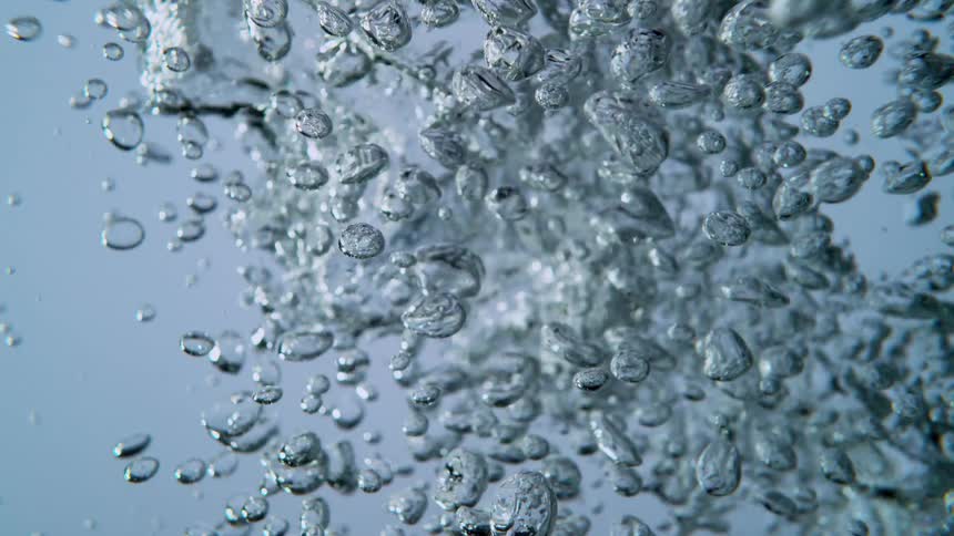 Crystal clear water is poured, creating a beautiful display of energetic bubbles rising in slow motion