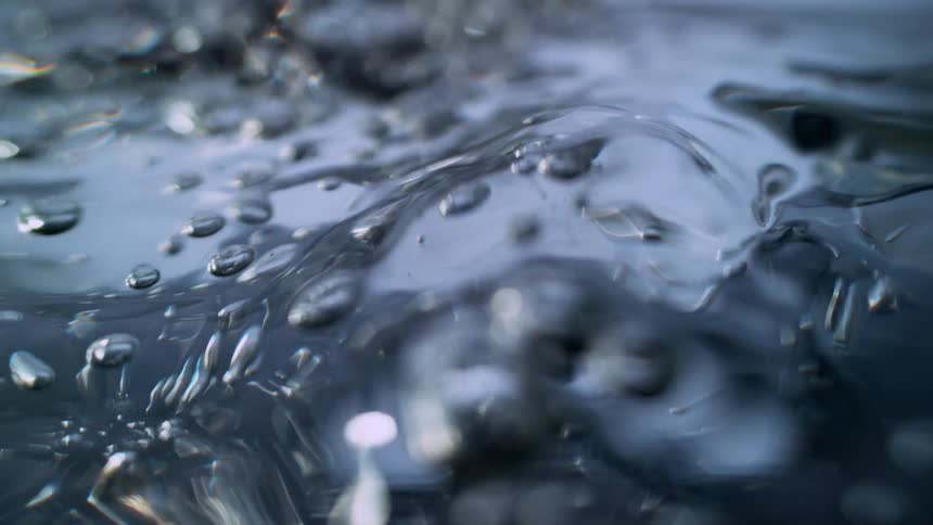 A mesmerizing slow-motion macro view of turbulent water with shimmering bubbles rising to the surface