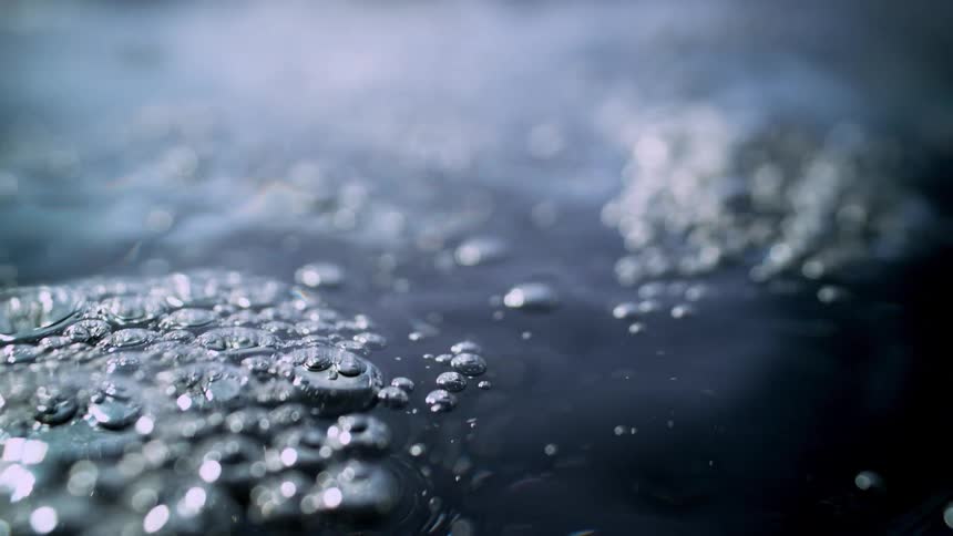 A hypnotic macro slow-motion shot of water gently boiling and creating mesmerizing bubbles on its surface