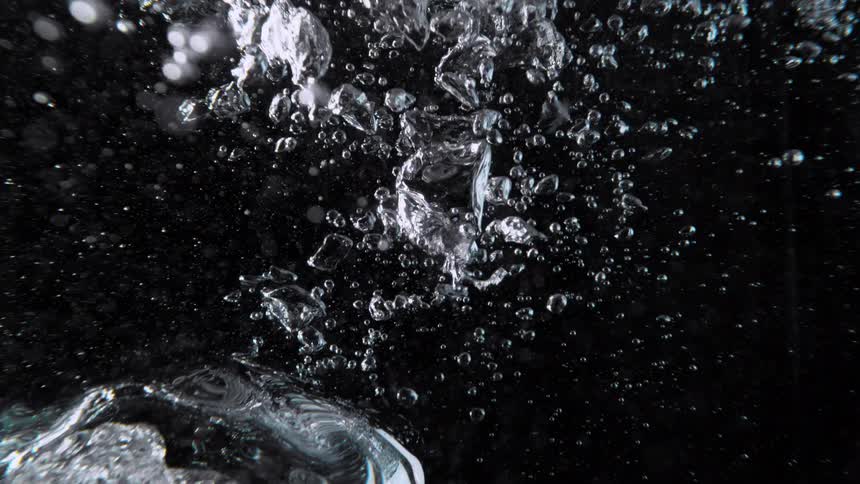 Abstract underwater view of air bubbles rising in slow motion on a black background