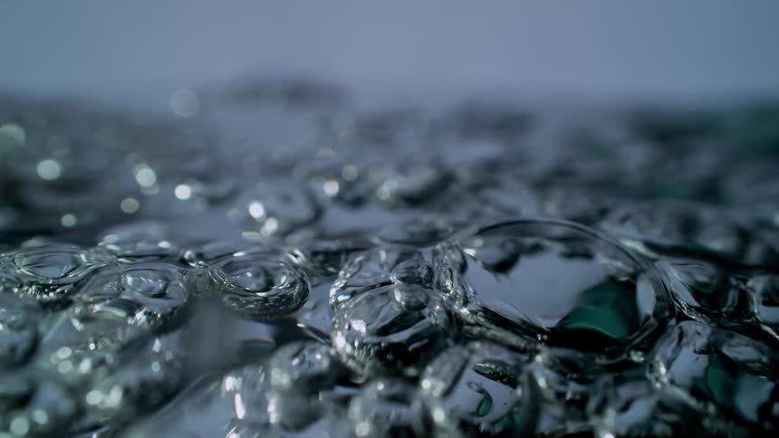 A dramatic super slow-motion macro shot of water bubbles boiling and popping on the surface