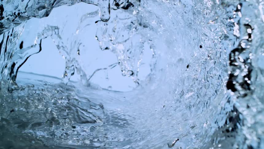 The inside of a crystal clear water wave barrels towards the camera in extreme slow motion