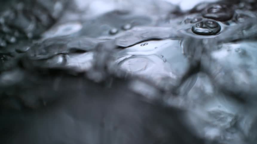 An abstract and dramatic slow-motion macro shot of water bubbling and undulating