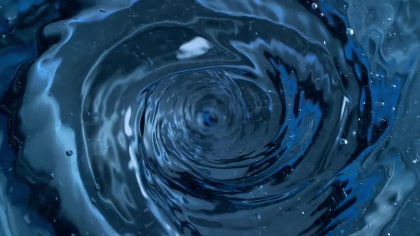 A dramatic top-down slow-motion view of a mesmerizing water vortex swirling in a deep blue liquid
