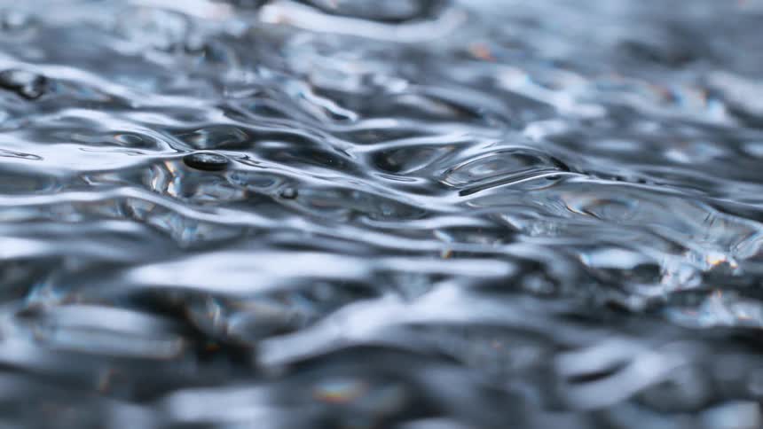 Slow motion macro footage captures the mesmerizing, undulating surface of clear water