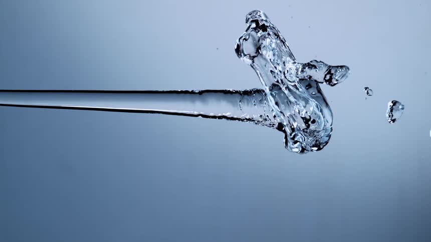 An isolated stream of crystal clear water splashes horizontally across the frame in super slow motion