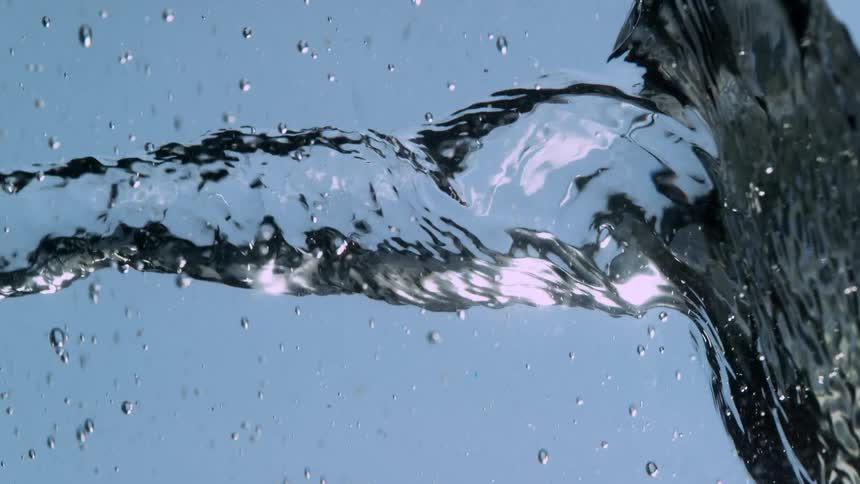 A super slow-motion macro shot shows a mesmerizing vortex of twisting clear water surrounded by droplets against a blue background