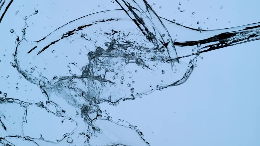 Two streams of clear water collide in a dramatic splash against a light blue background in ultra slow motion