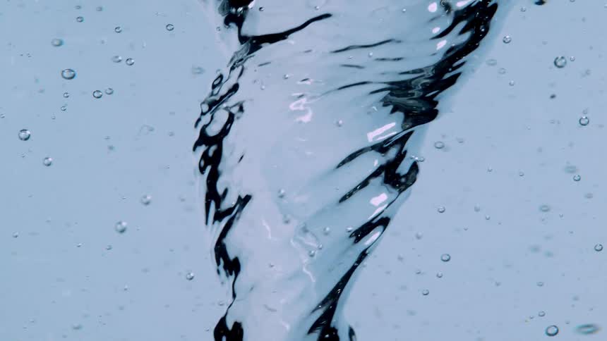 A powerful vortex swirls in clean, clear water, creating a mesmerizing whirlpool against a light blue background in slow motion