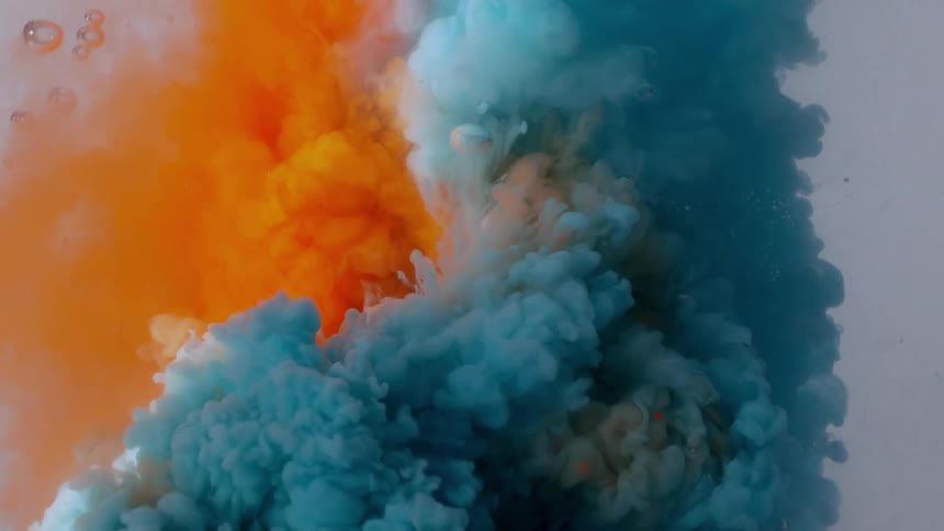 Vibrant orange and light blue paint bloom and swirl together like abstract clouds in water in super slow motion