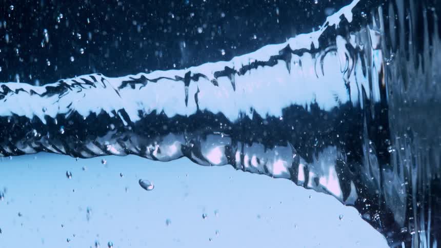 A mesmerizing slow-motion close-up of a swirling water vortex twisting against a deep blue background
