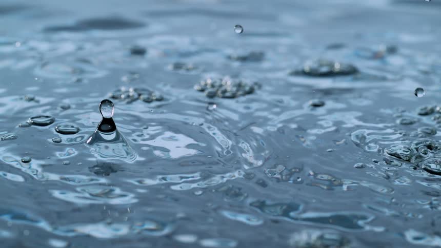 Mesmerizing super slow-motion close-up of water droplets dripping and creating intricate ripples on a clear surface