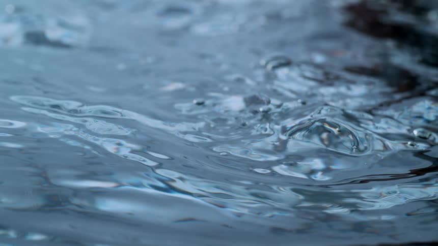 A mesmerizing close-up of a dark blue water surface rippling gently in super slow motion