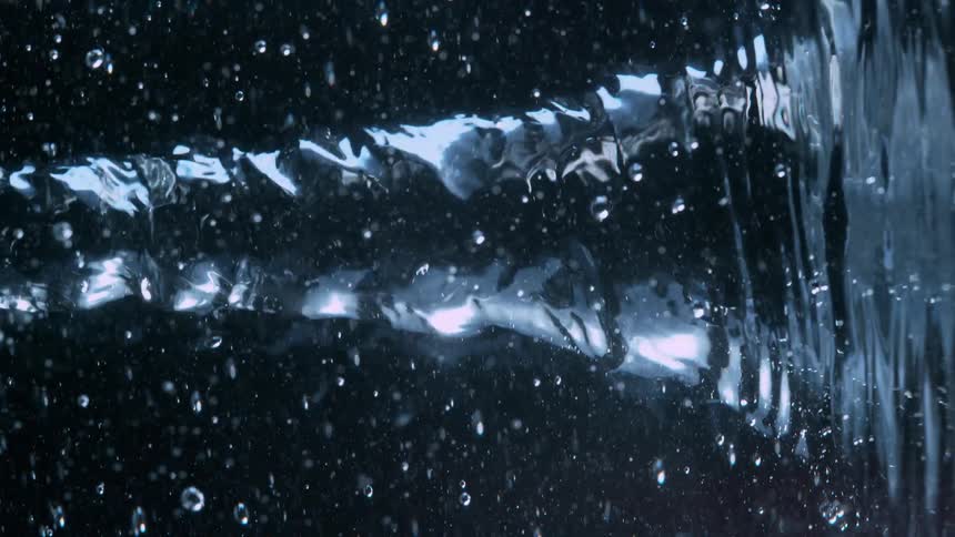 A powerful, twisting stream of water flows horizontally in super slow motion against a black background