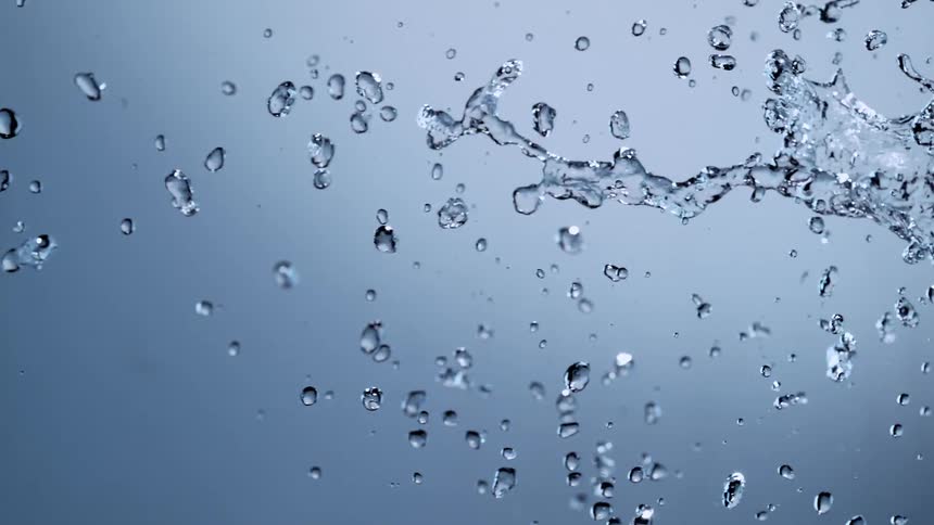 Super slow motion footage captures a horizontal stream of water splashing and forming droplets against a clean background