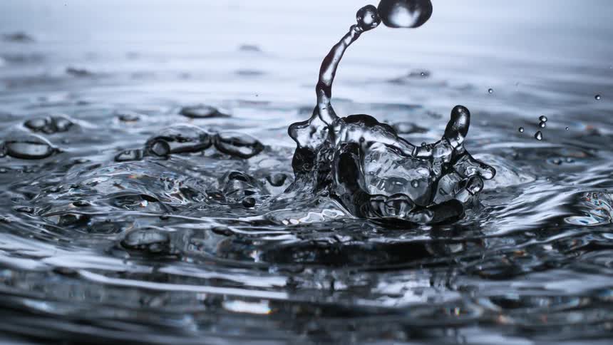 Mesmerizing super slow-motion close-up of water droplets falling and creating ripples and splashes on the surface