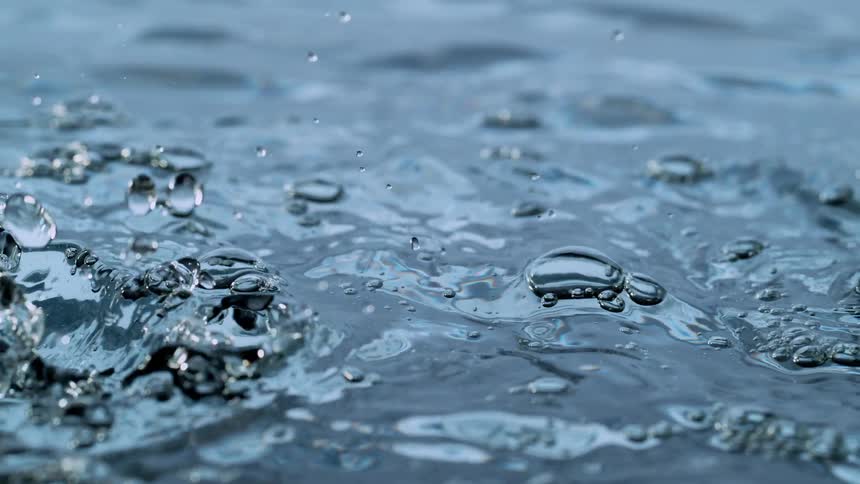 A mesmerizing extreme close-up of water droplets splashing onto a calm surface in super slow motion