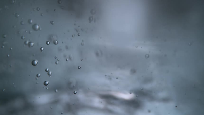 An abstract macro shot of bubbles rising slowly through clear water, creating a mesmerizing effect
