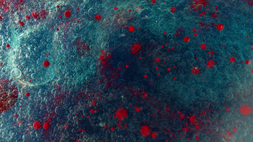 A mesmerizing macro shot of red spheres and tiny bubbles floating in a turquoise and dark blue liquid