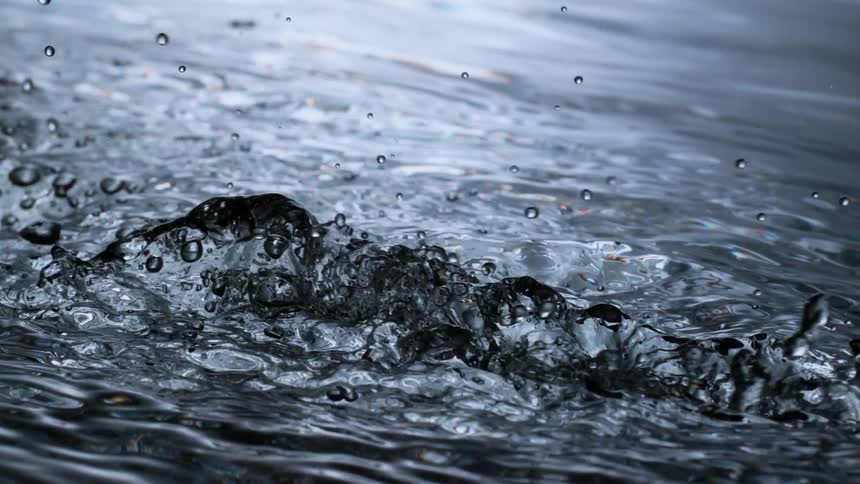 Mesmerizing super slow-motion close-up shot of dark, silver-toned water splashing and churning