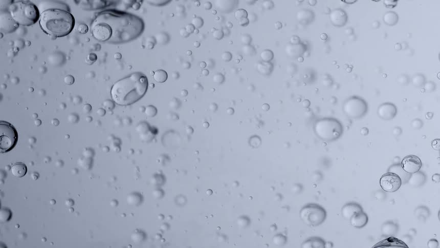 A tranquil macro view of clear bubbles suspended in a still, transparent liquid, captured in slow motion