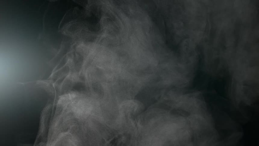 Slow-motion ethereal white smoke gently billows and swirls against a dark, atmospheric background