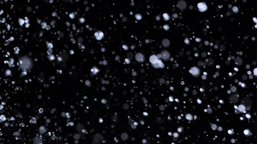 A mesmerizing slow-motion display of water droplets splashing and falling through the air against a black backdrop