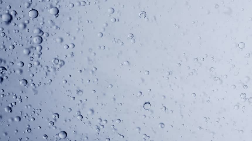 A macro shot shows air bubbles of various sizes floating in a clear, light blue viscous liquid
