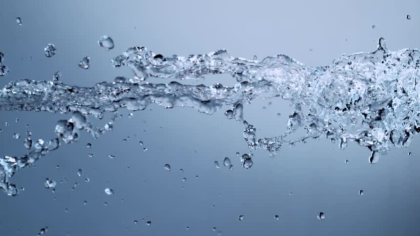 Super slow motion close up of a horizontal stream of clear water splashing against a blue background