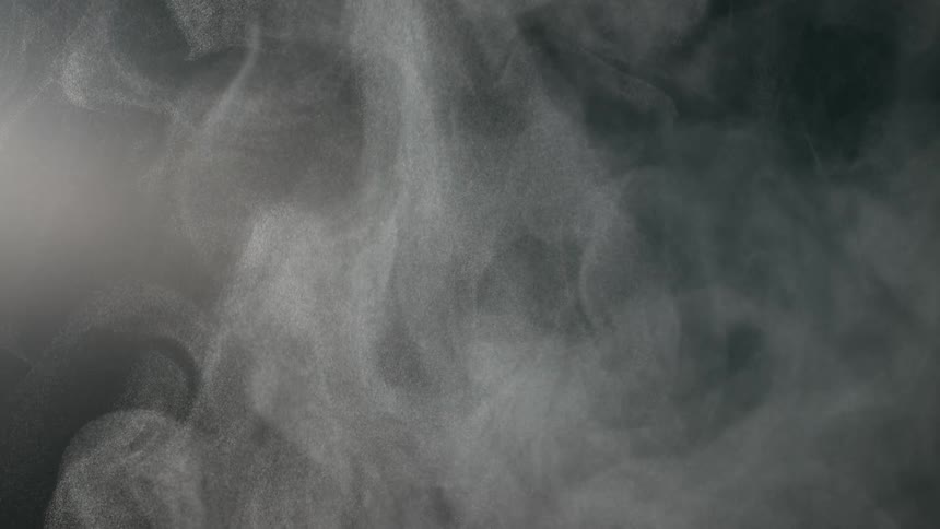 Slow motion abstract shot of white particles resembling smoke or steam swirling against a dark background