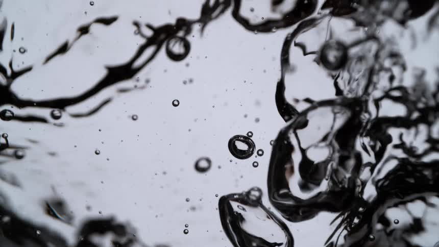 An abstract, super slow-motion macro shot of clear water energetically bubbling and boiling against a white background