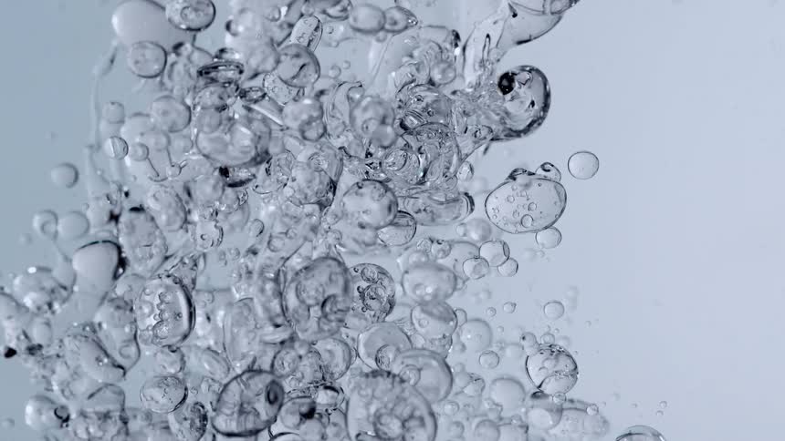 A super slow-motion macro shot captures clear bubbles of varying sizes rising in water against a clean background