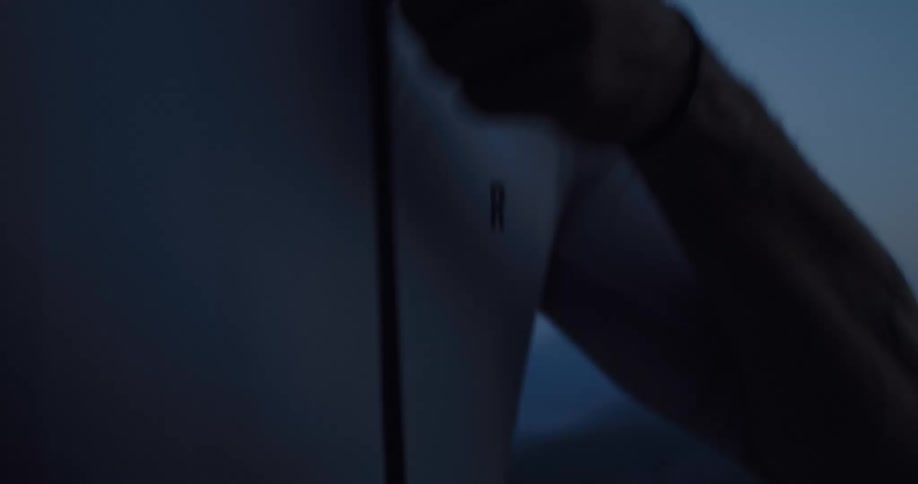 An athlete zips up a white performance jacket in slow motion against a twilight mountain backdrop