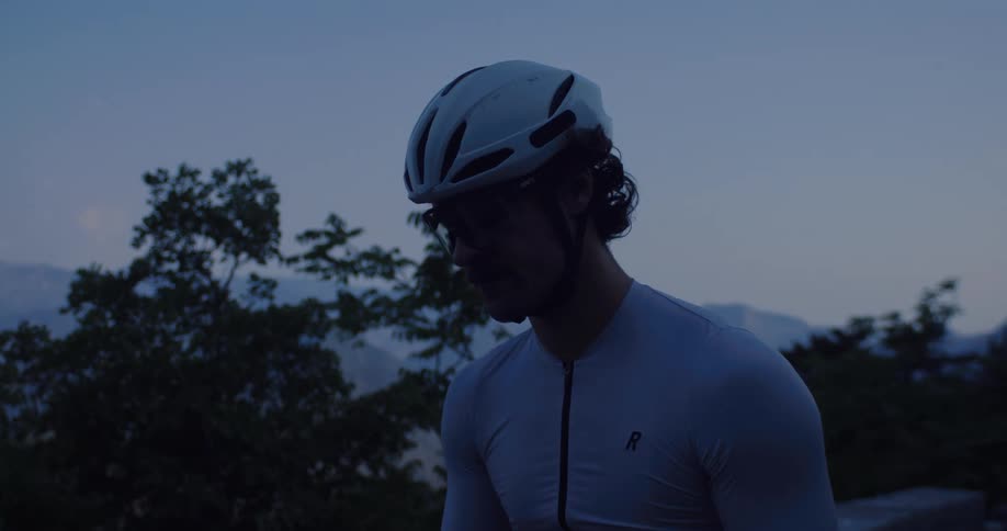 A professional cyclist takes a moment to rehydrate from his water bottle during a dusk ride in the mountains