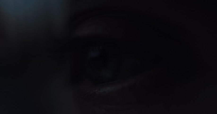 A macro shot shows a human eye waking up and opening slowly in a dark, moody setting