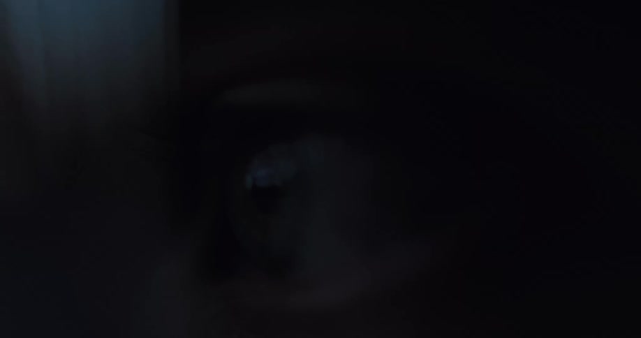 An extreme close-up of a frightened eye wide open in the dark