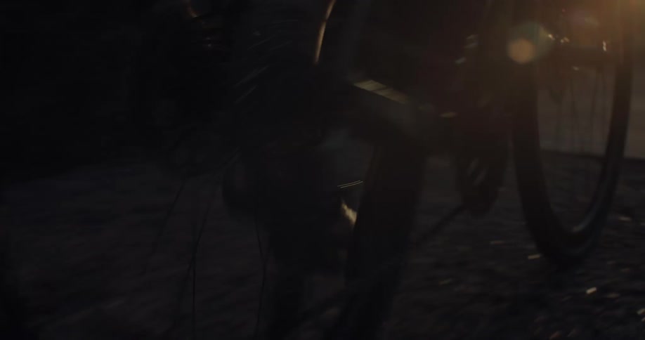 Close-up of a cyclist's feet pedaling a bicycle on a road during the golden hour