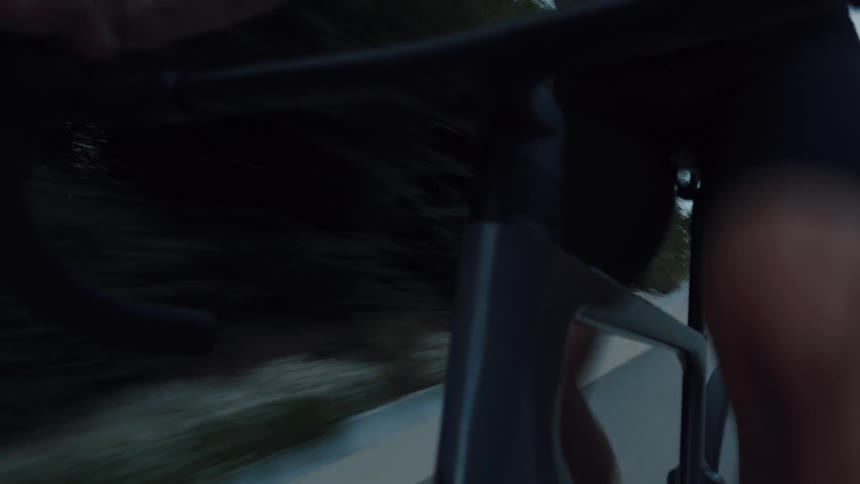 Dynamic close-up shot of a cyclist pedaling at speed on a modern road bike during an evening ride