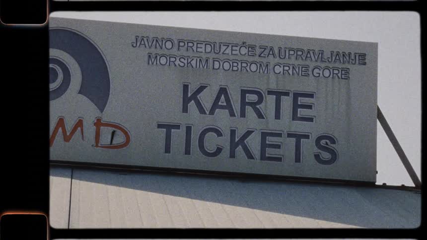 A grainy, vintage-style shot shows a weathered 'Tickets' sign in Montenegro